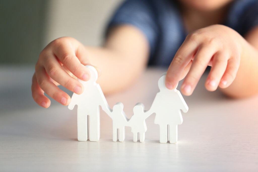 Child holding figure in shape of happy family, closeup. Adoption concept